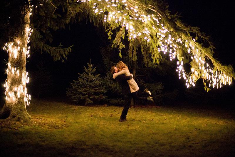 a woman standing under a tree covered in lights