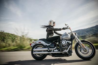 a woman riding a motorcycle down a road