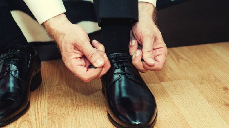 a man in a suit tying a pair of black shoes