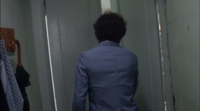 a man in a blue suit standing in a hallway