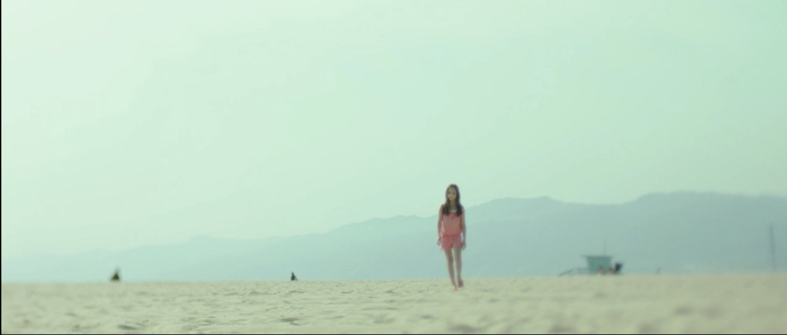 a woman in a pink dress standing on a beach