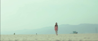 a woman in a pink dress standing on a beach