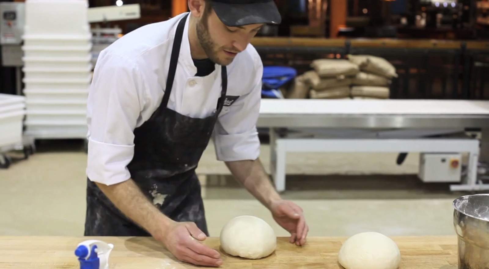 a man in an apron is kneading some doughnuts