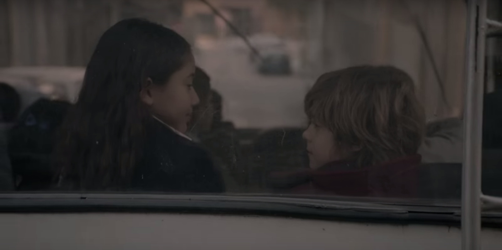 two young girls looking out the window of a bus