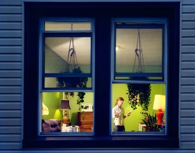 a woman standing in front of a window next to a lamp