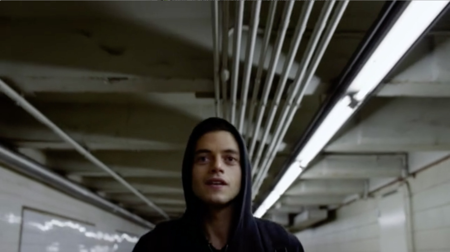 a man in a black hoodie standing in a parking garage