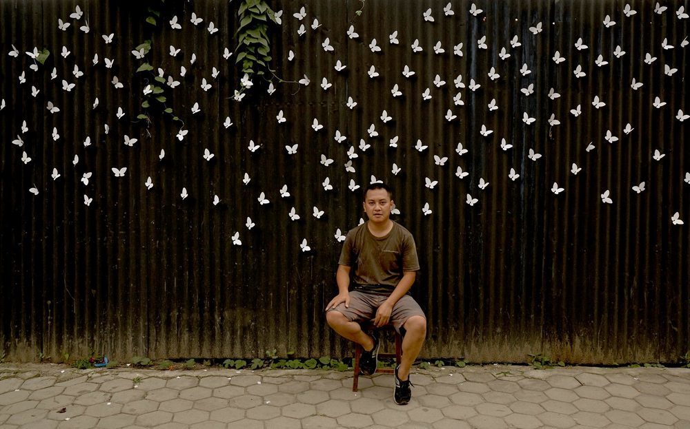 a man sitting on a chair in front of a fence