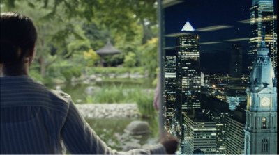 a man looking out a window at a city at night