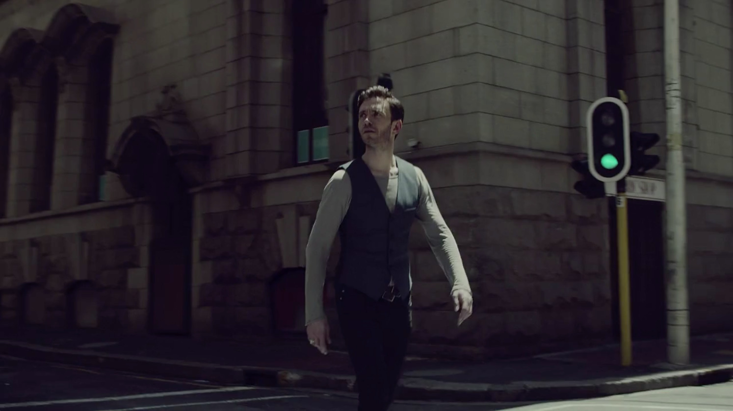 a man walking across a street next to a traffic light