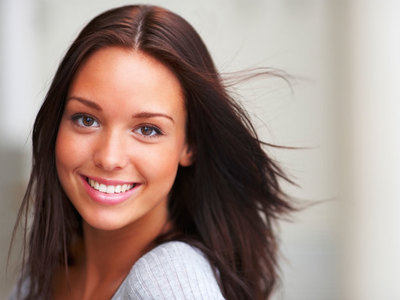 a woman with long brown hair smiling at the camera