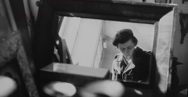 a black and white photo of a woman looking in a mirror