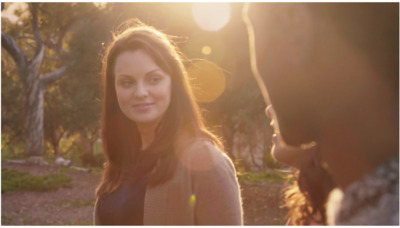 a woman standing next to a man in a park