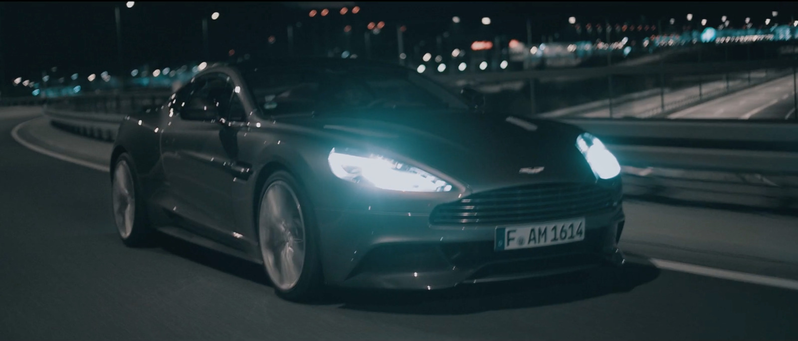 a black car driving down a street at night