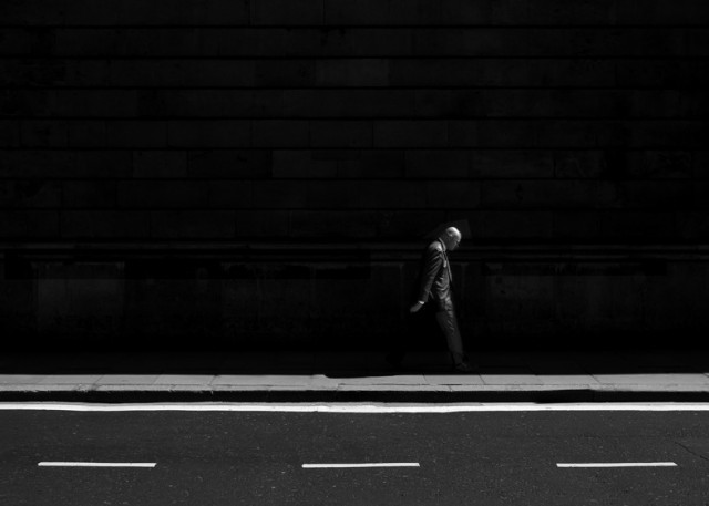 a man walking down a street next to a building