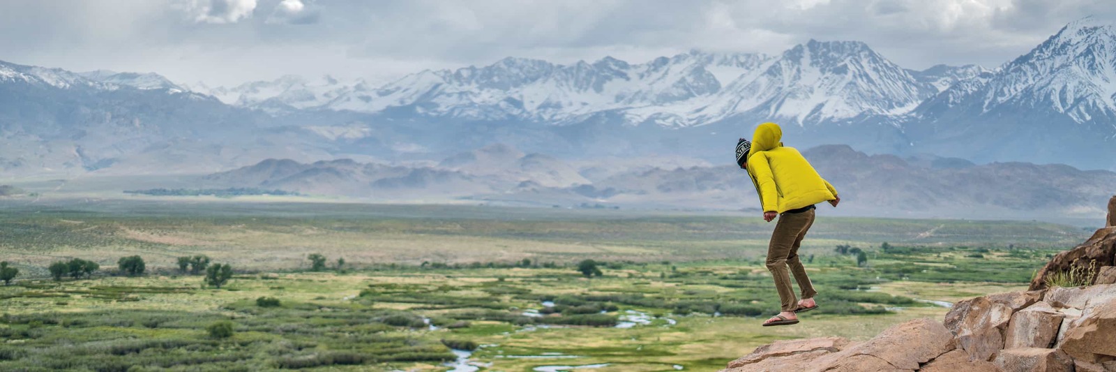 a person in a yellow jacket standing on a rock