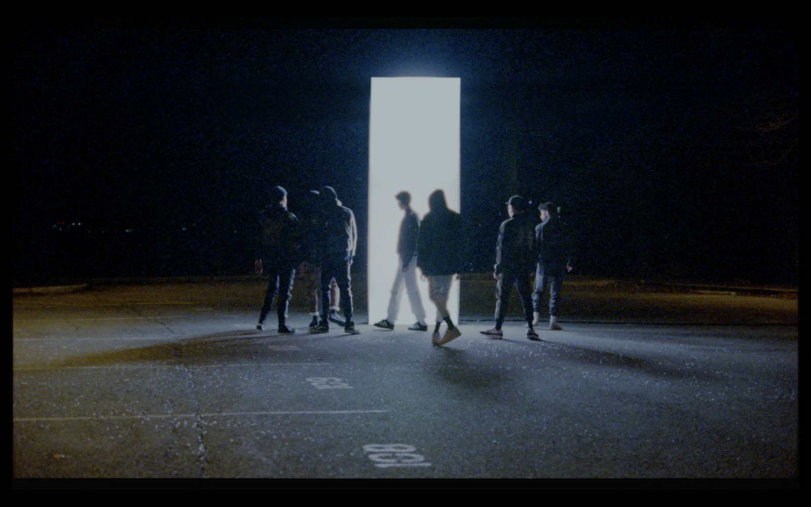 a group of people standing in a parking lot at night