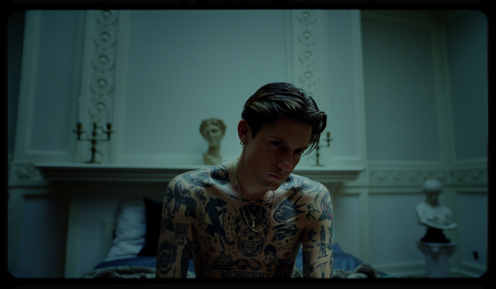 a man with tattoos on his body sitting on a bed