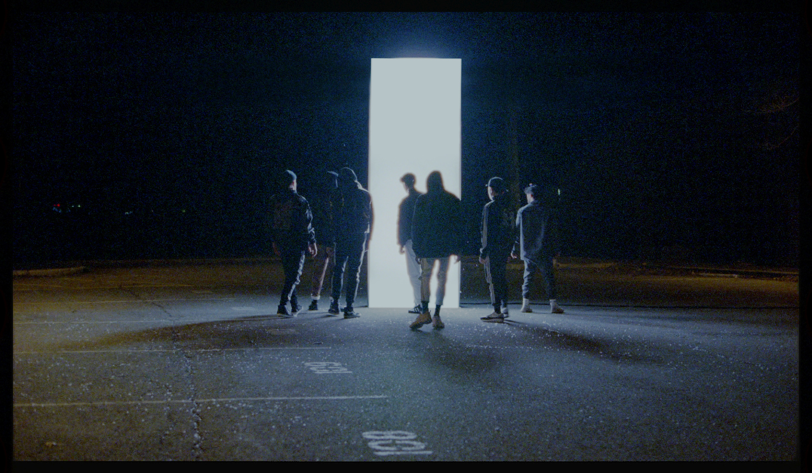 a group of people standing in a parking lot at night