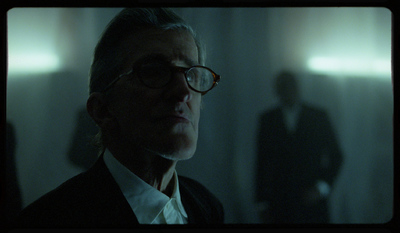 a man in a suit and glasses in a dark room