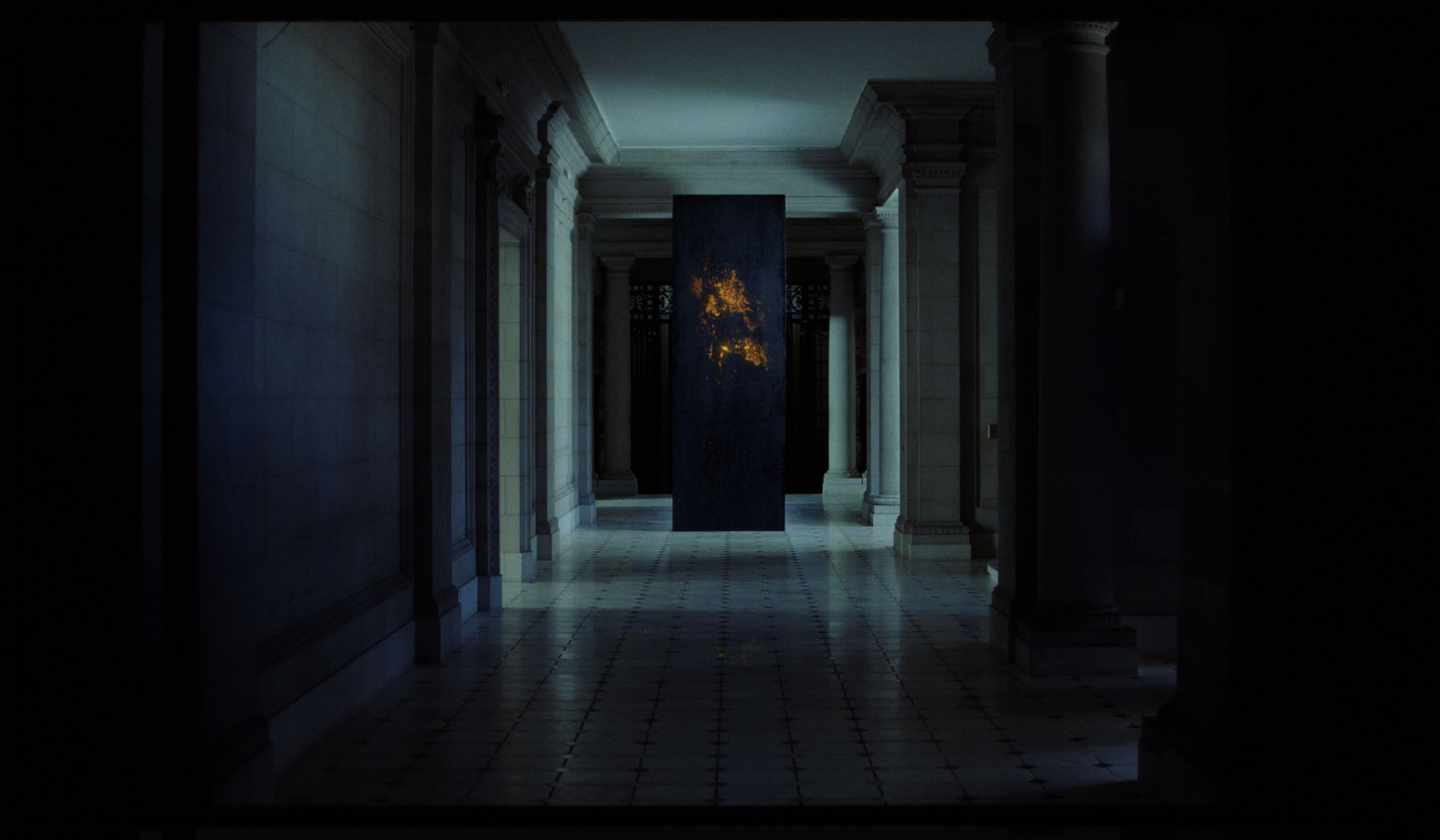 a dark hallway with columns and a fire hydrant