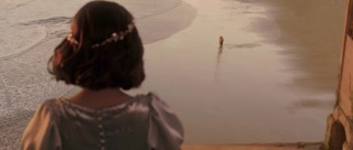 a woman standing on a beach next to a body of water