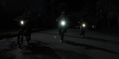 a couple of people riding bikes down a street at night