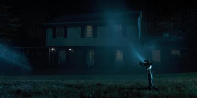 a person holding a flashlight in front of a house