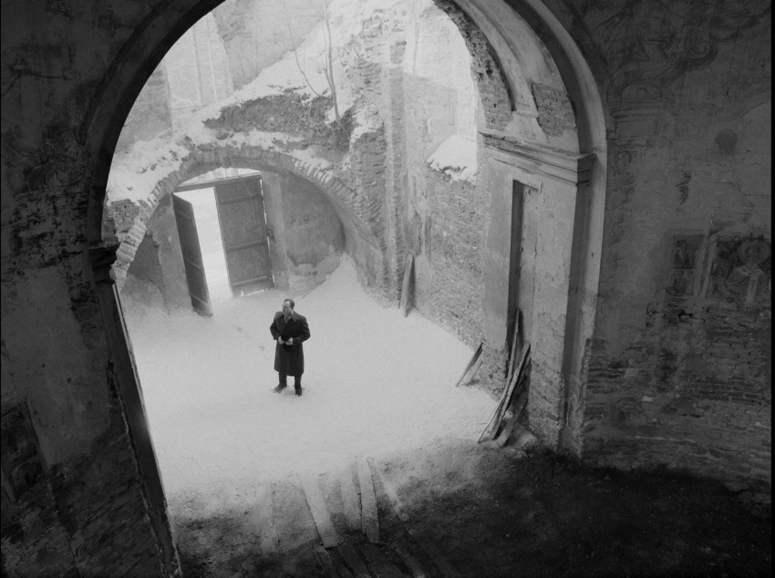 a black and white photo of a man standing in a tunnel