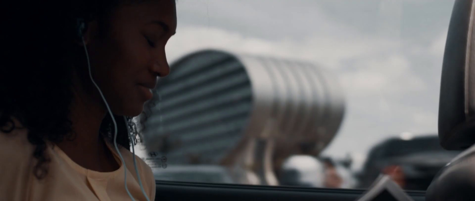 a woman sitting in a car listening to headphones