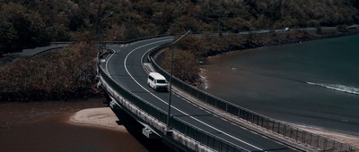 a car driving on a bridge over a body of water