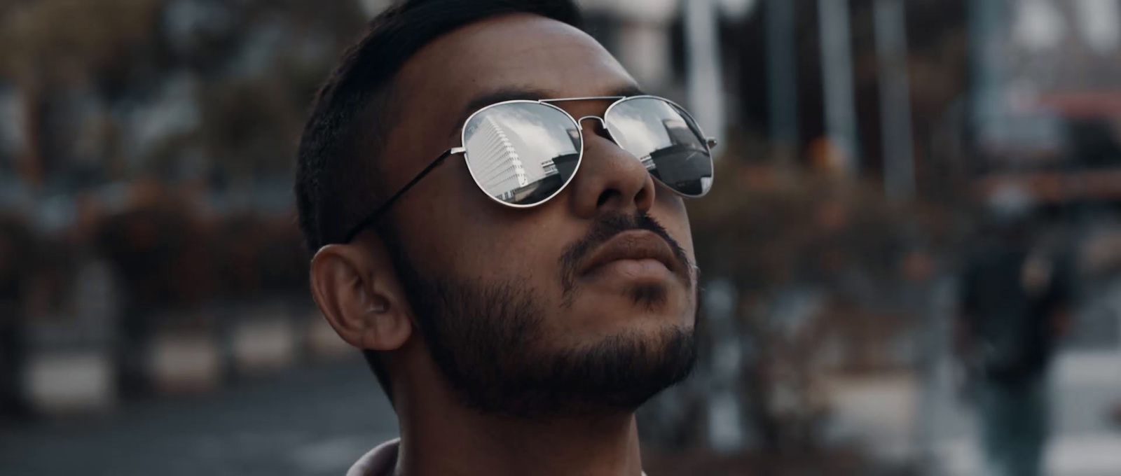 a man wearing mirrored sunglasses looks off into the distance