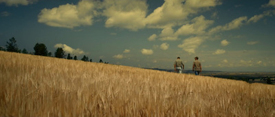 a couple of people standing on top of a dry grass field