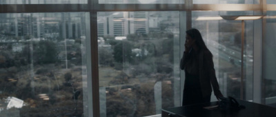 a woman standing in front of a window looking out at a city