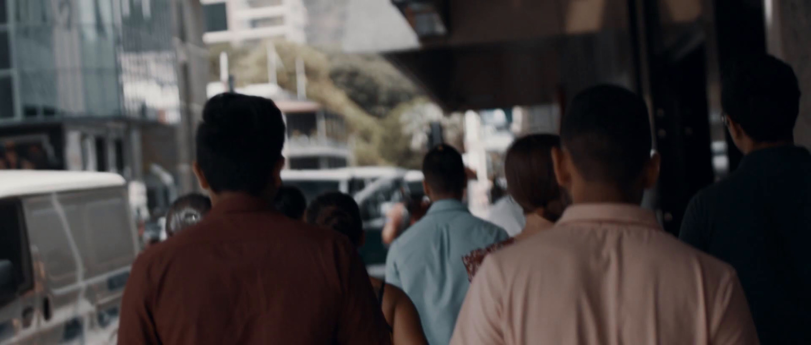 a group of people walking down a street next to tall buildings