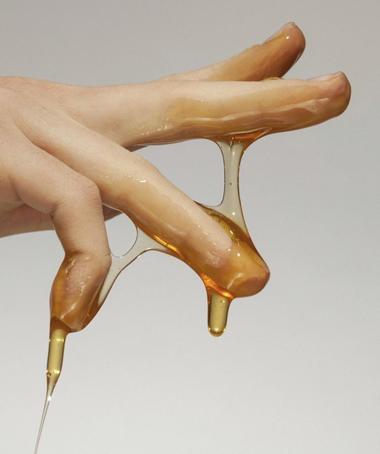 a hand holding a spoon with liquid pouring out of it