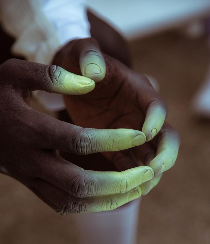 a person holding a cup with their hands painted green