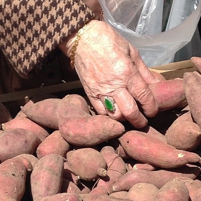 a person holding a box full of sweet potatoes