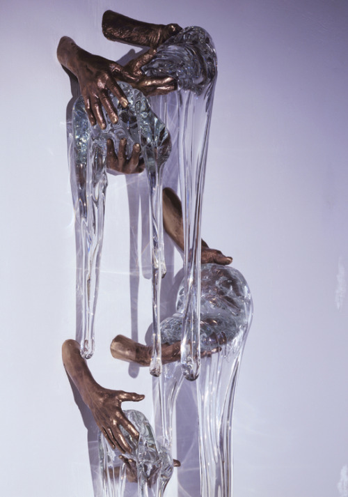 a sculpture of hands reaching for a piece of glass