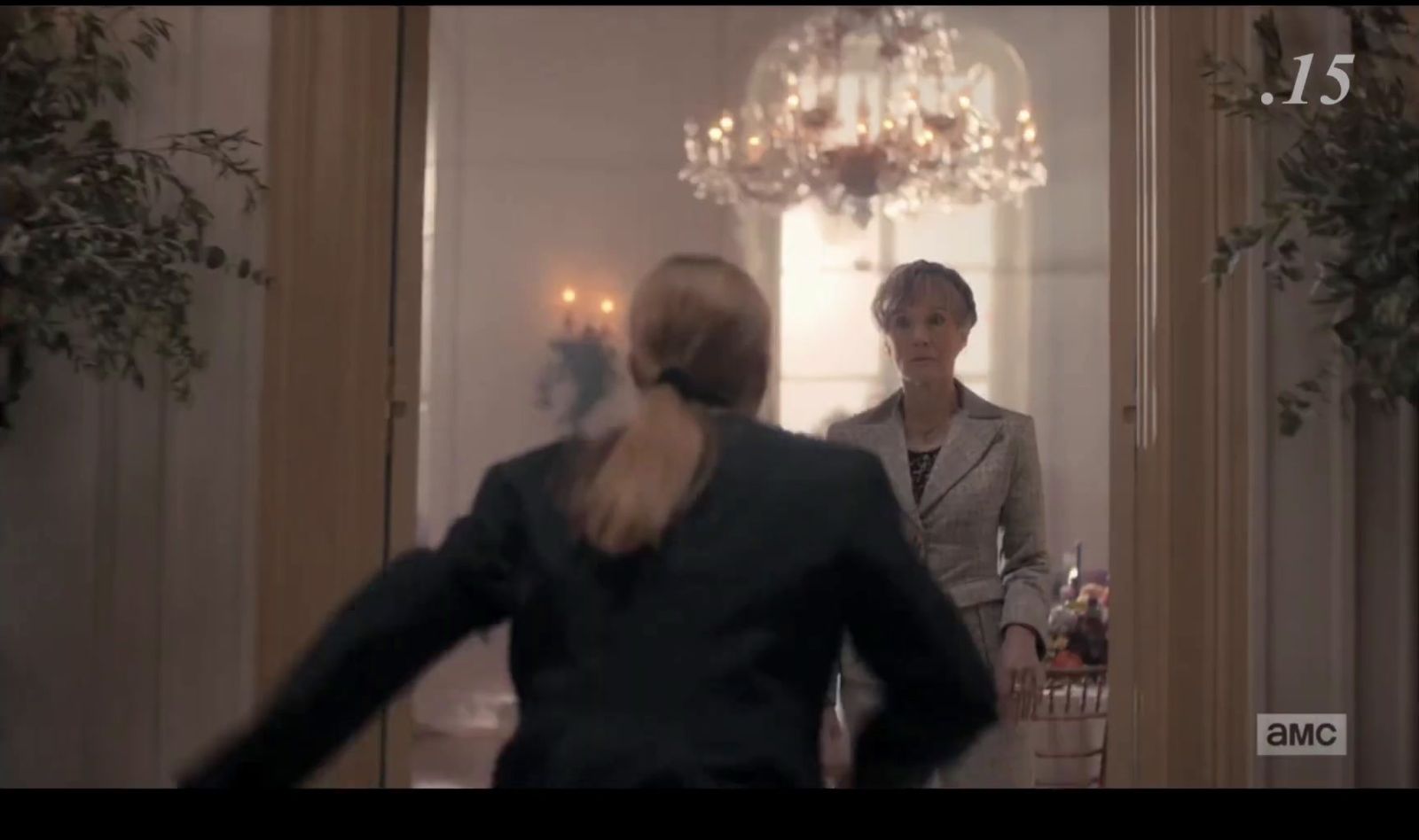 a woman in a suit and a woman in a dress in a hallway