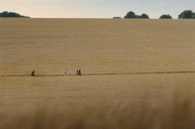 a group of people walking across a dry grass field