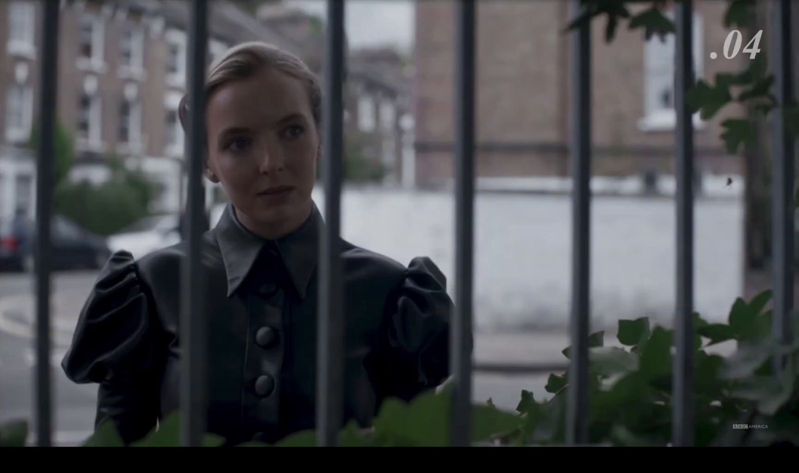 a woman standing behind a fence in front of a building