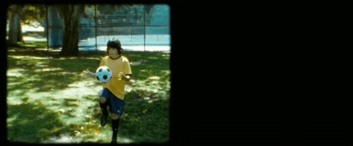 a young boy holding a soccer ball in a park