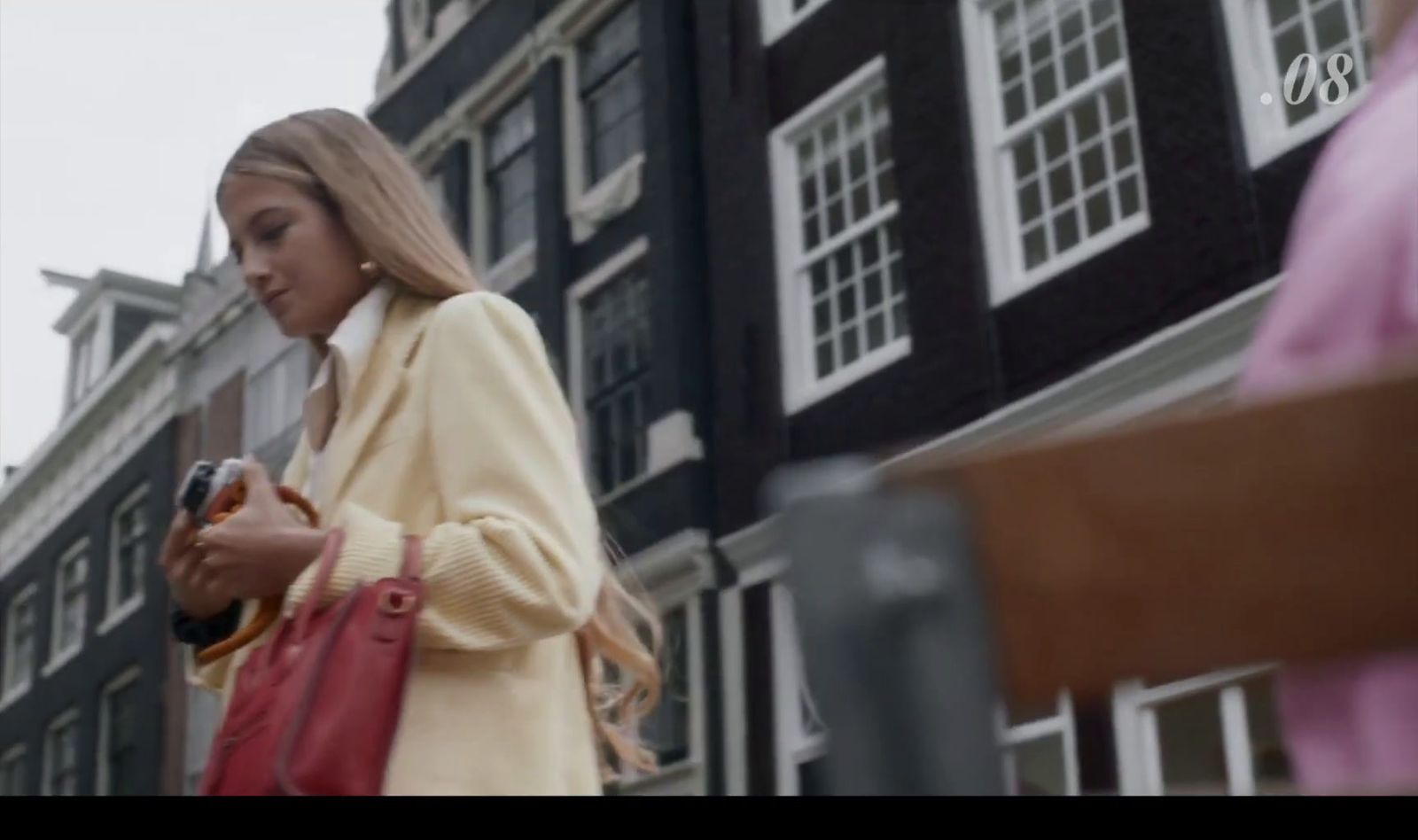 a woman standing in front of a building looking at her cell phone