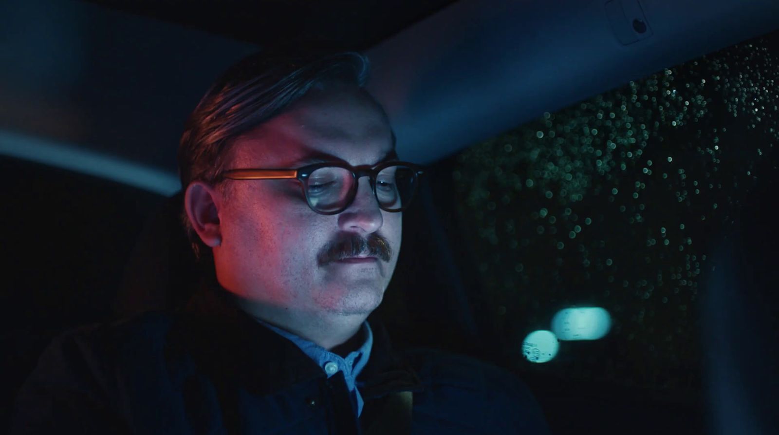 a man with glasses and a mustache in the dark