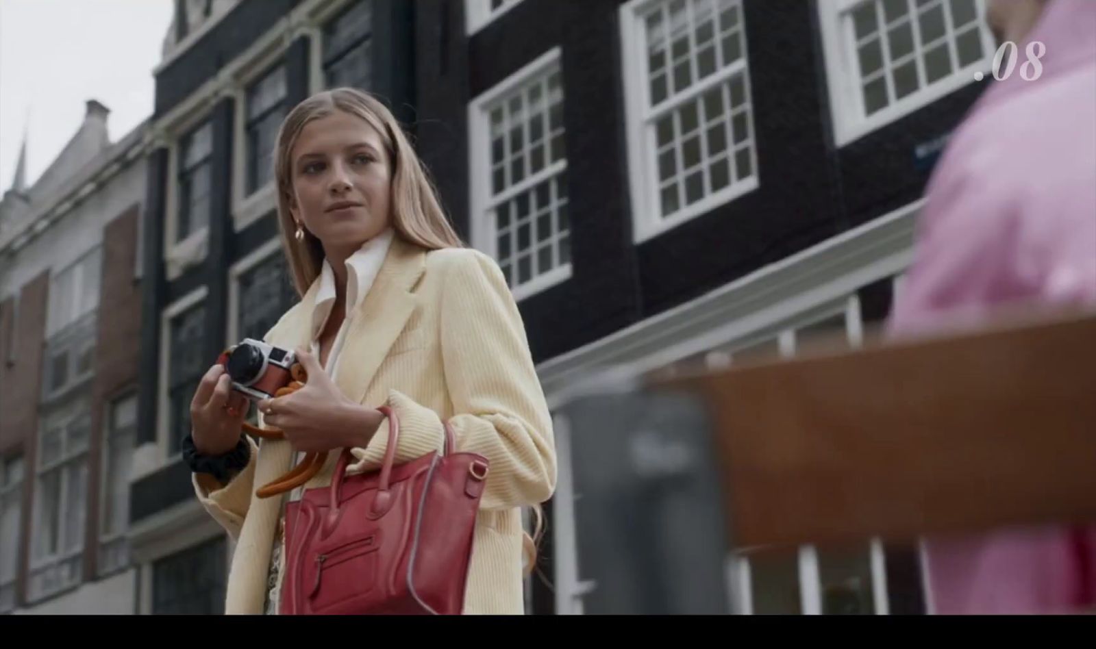 a woman is holding a camera and a purse