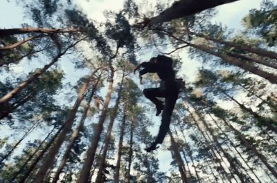 a person jumping in the air in the middle of a forest