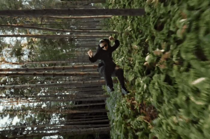 a man in a black suit is walking on a rope bridge