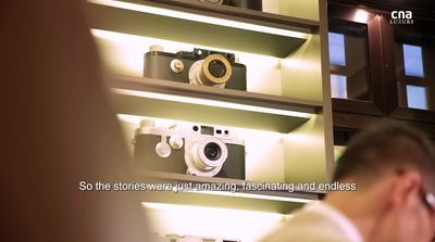 a man sitting in front of a display of cameras