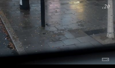 a wet sidewalk with a pole and a street sign