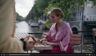 a woman sitting at a table writing on a piece of paper